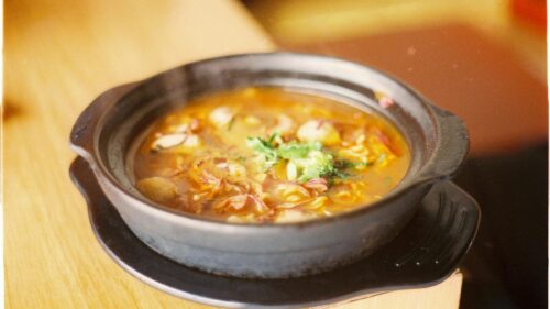 A delicious steaming hot soup served in a rustic black bowl.