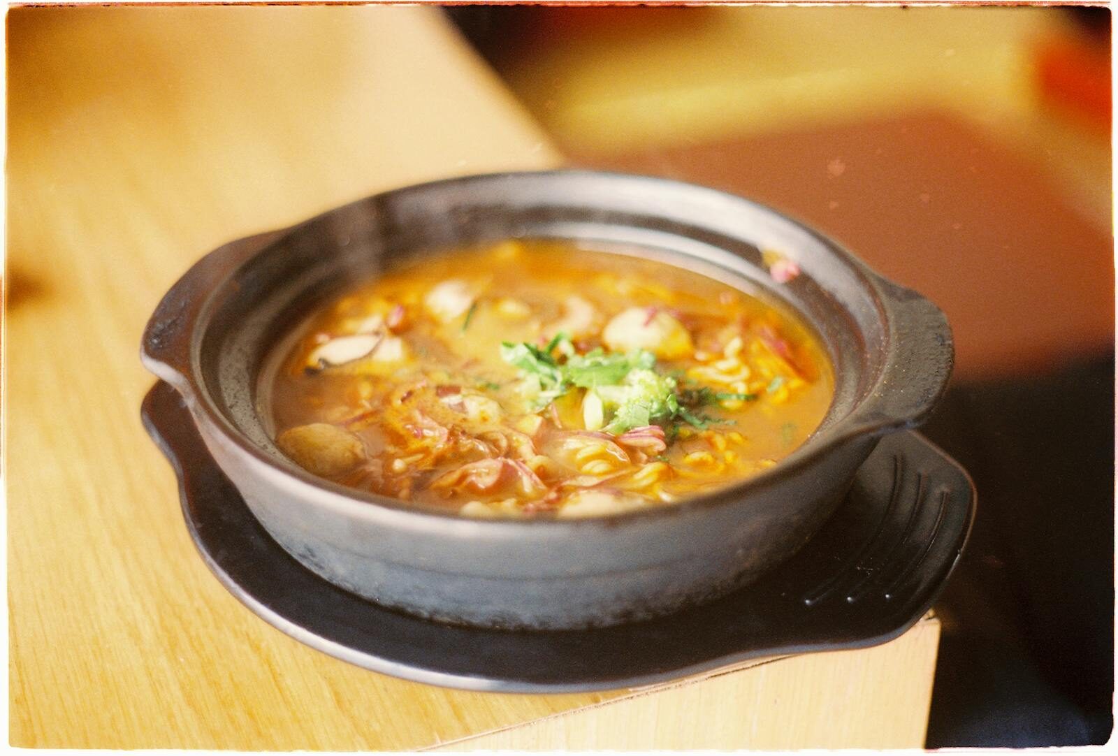 A delicious steaming hot soup served in a rustic black bowl.